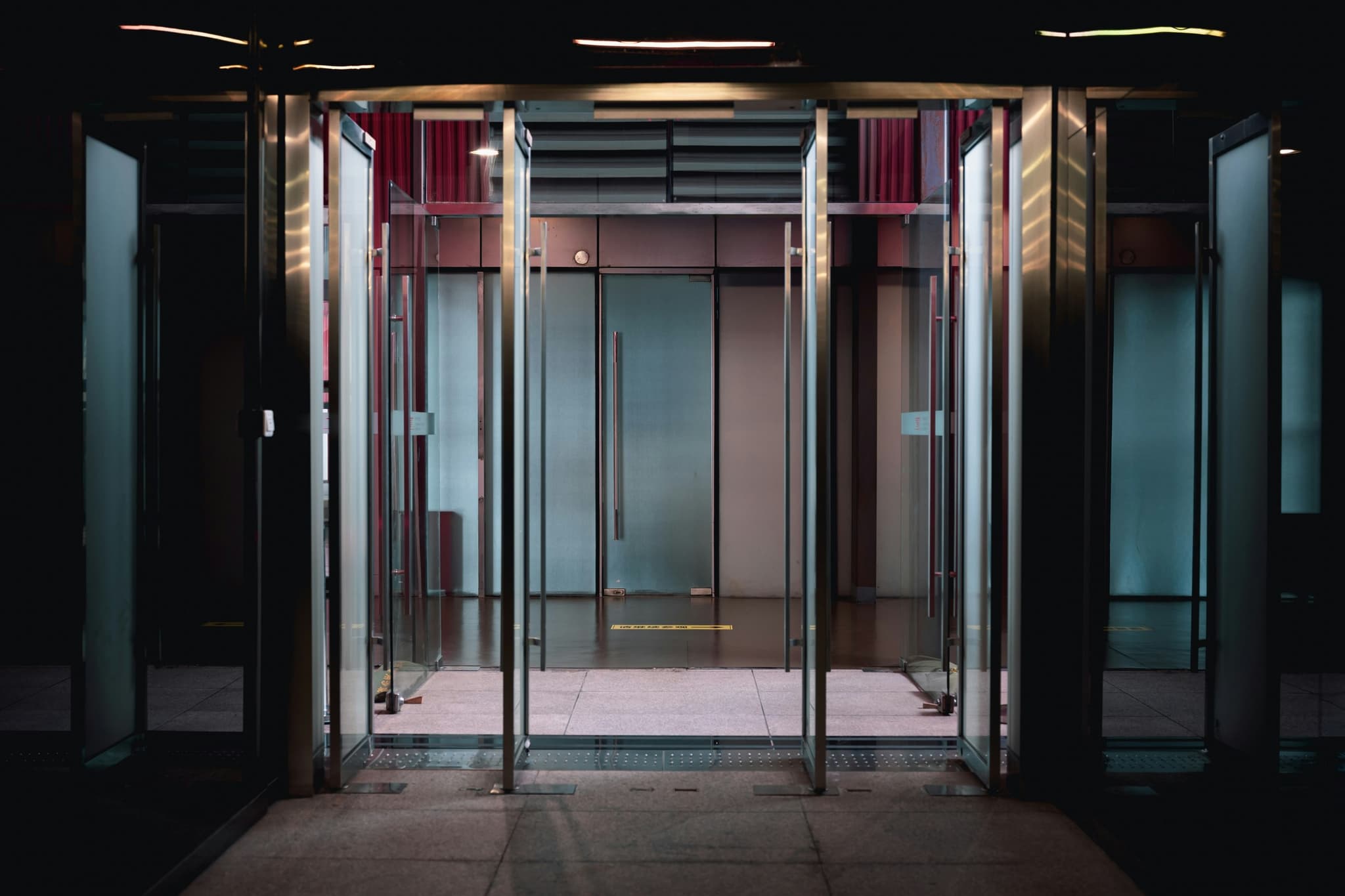 Open glass swing-door entrance leading into a building vestibule
